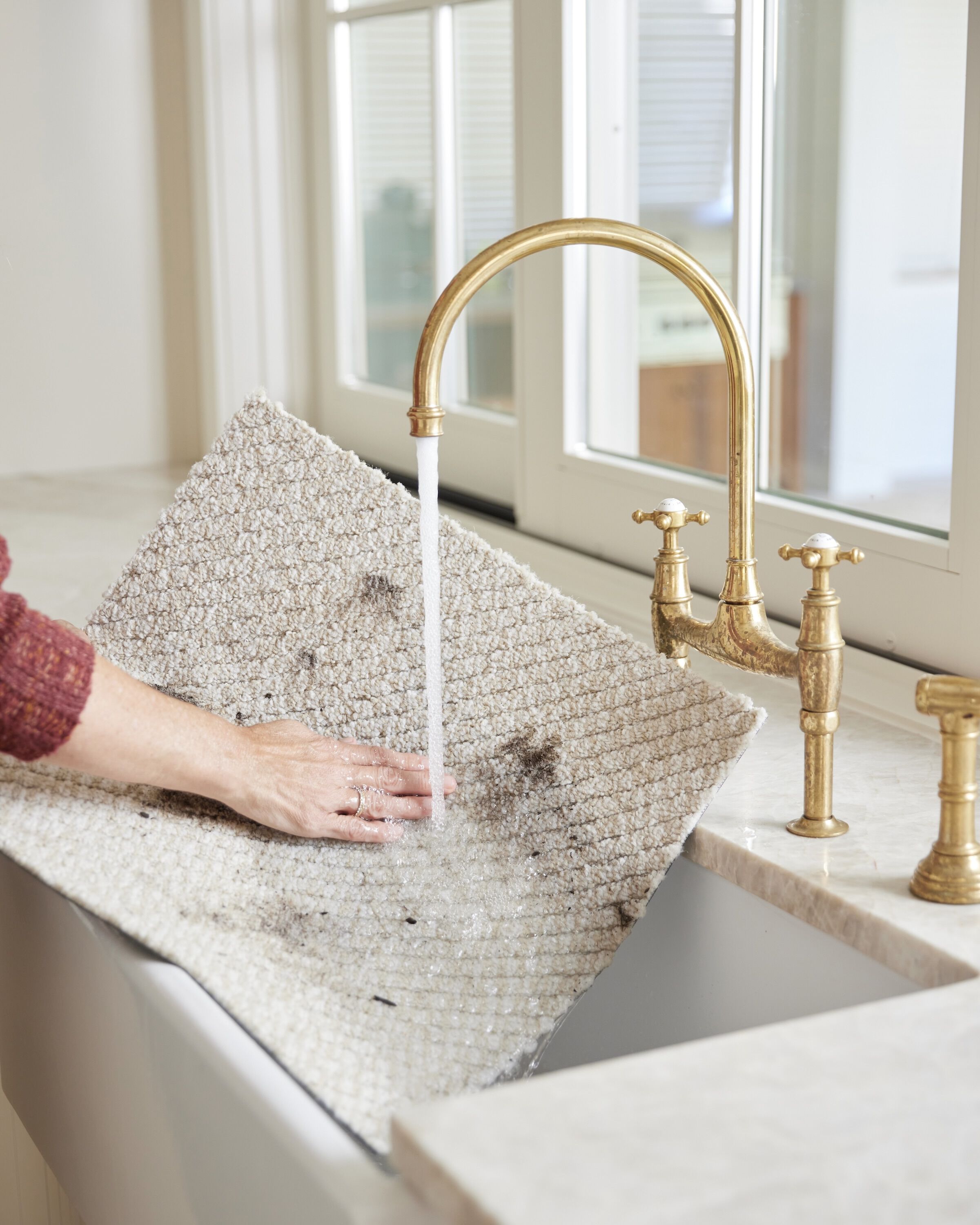 Person rinsing Hit The Road in Bone FLOR carpet tile stained with dirt in the sink. 
