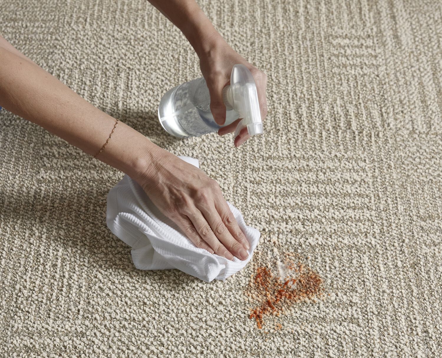 Hands of a person cleaning a spill on a FLOR carpet tile.