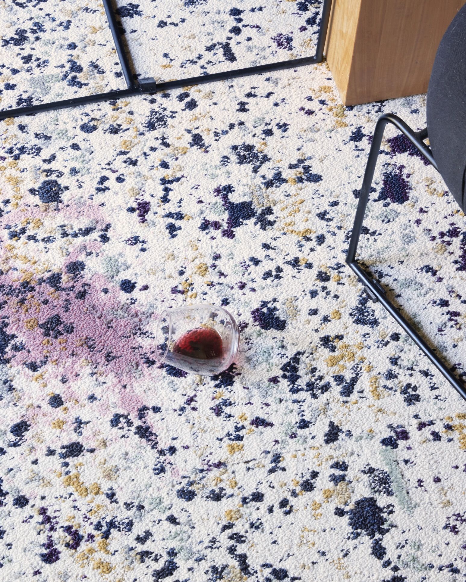 Close view of a spilled glass of red wine on Painter's Palette carpet tiles.. 